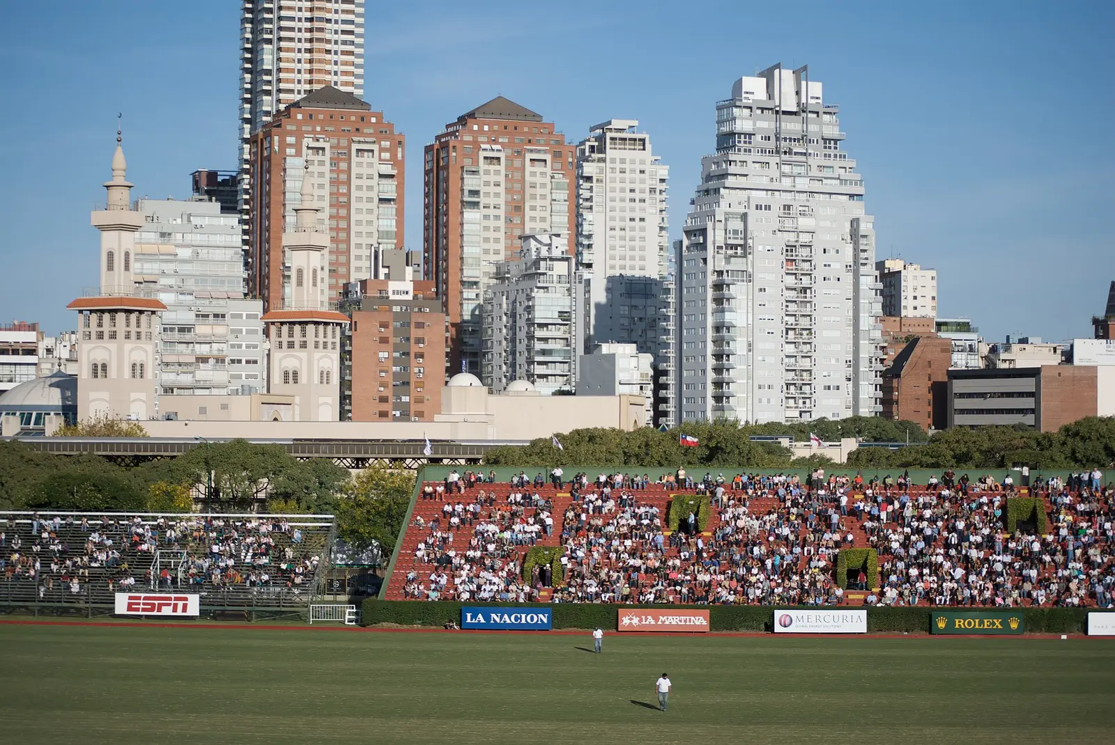 Spectators in the stands of the Campo Argentino de Polo in Palermo with apartment towers behind the pitch